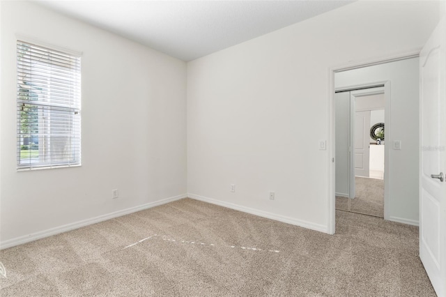 carpeted empty room featuring baseboards