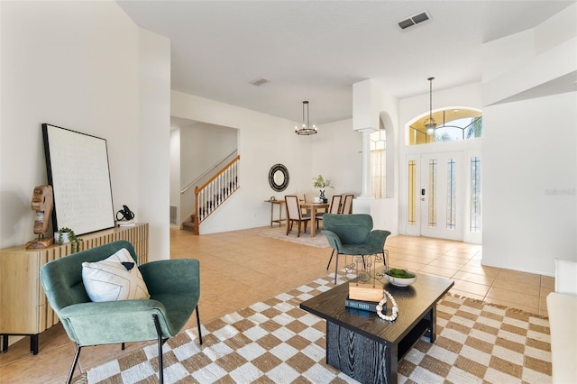 living room featuring light tile patterned flooring, visible vents, and stairway