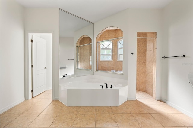 full bathroom featuring a bath, tile patterned floors, a tile shower, and baseboards