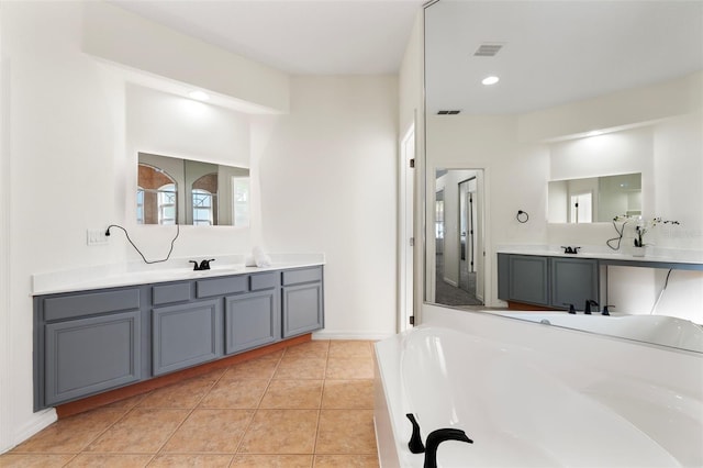 full bath featuring tile patterned floors, visible vents, a garden tub, two vanities, and a sink