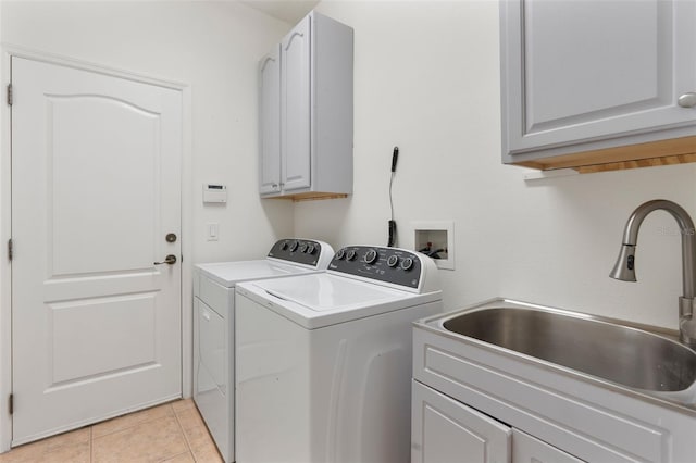 clothes washing area featuring washing machine and clothes dryer, light tile patterned floors, cabinet space, and a sink