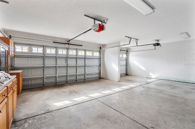 garage featuring concrete block wall and a garage door opener