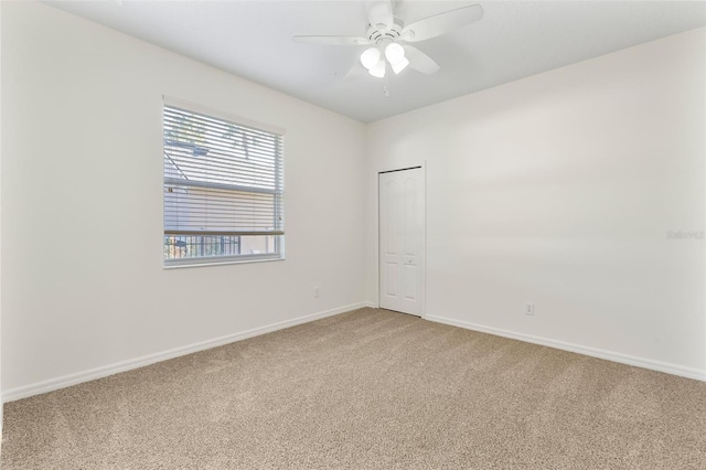 spare room with baseboards, light carpet, and a ceiling fan