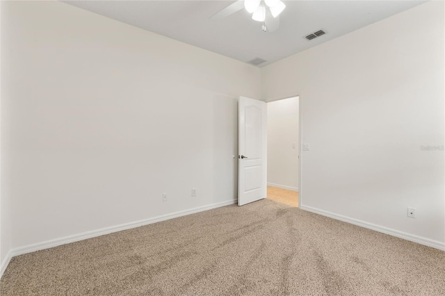 empty room with visible vents, light colored carpet, baseboards, and a ceiling fan