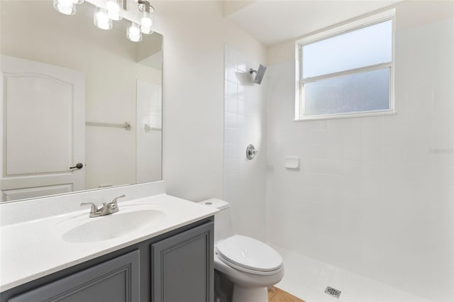 full bathroom featuring toilet, vanity, and a tile shower