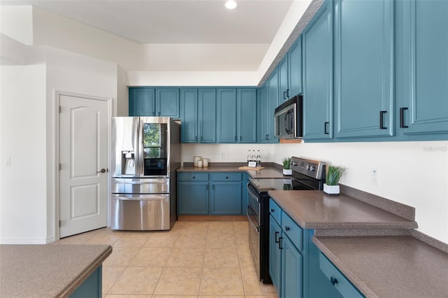 kitchen featuring dark countertops, blue cabinetry, light tile patterned flooring, and stainless steel appliances