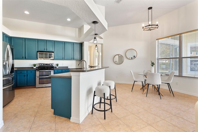 kitchen featuring dark countertops, blue cabinetry, light tile patterned floors, appliances with stainless steel finishes, and a kitchen breakfast bar