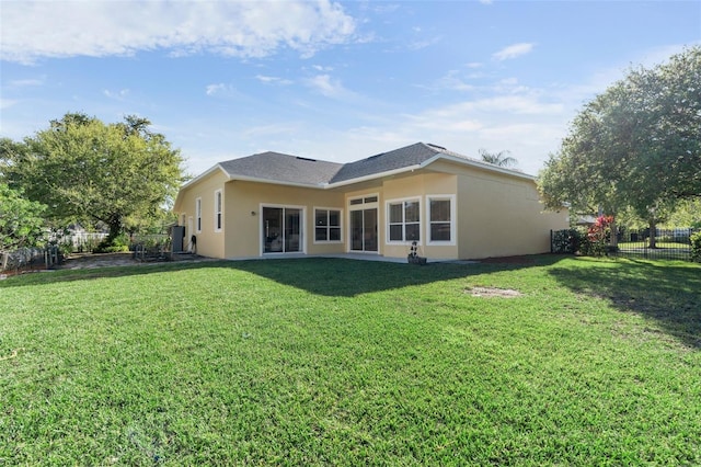 back of property with stucco siding, a lawn, and fence