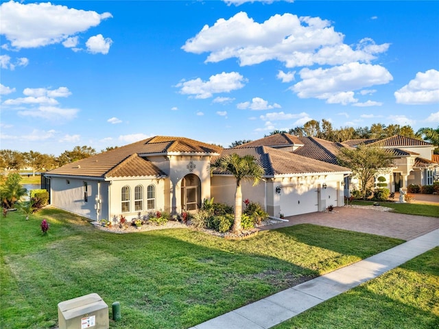 mediterranean / spanish-style house featuring a front yard, stucco siding, a garage, a tile roof, and decorative driveway