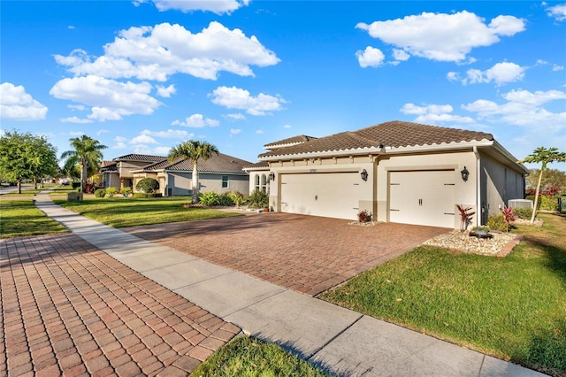 mediterranean / spanish-style home with a tiled roof, a front yard, stucco siding, decorative driveway, and a garage