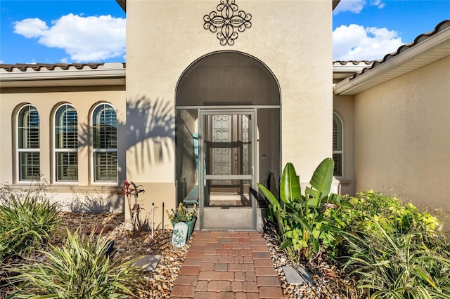 entrance to property with stucco siding and a tile roof