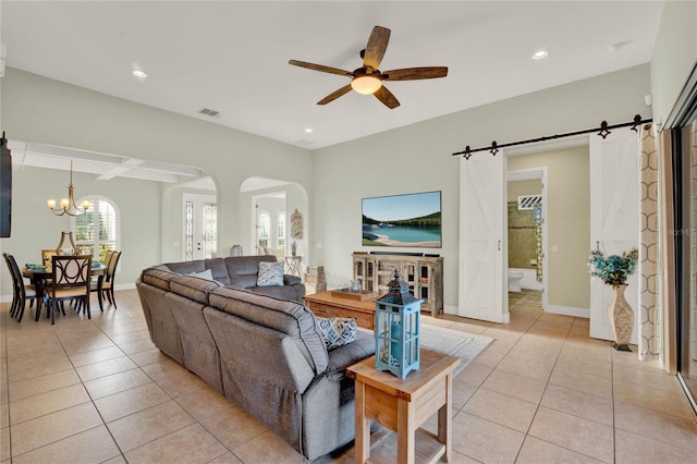 living room featuring light tile patterned floors, visible vents, baseboards, arched walkways, and a barn door