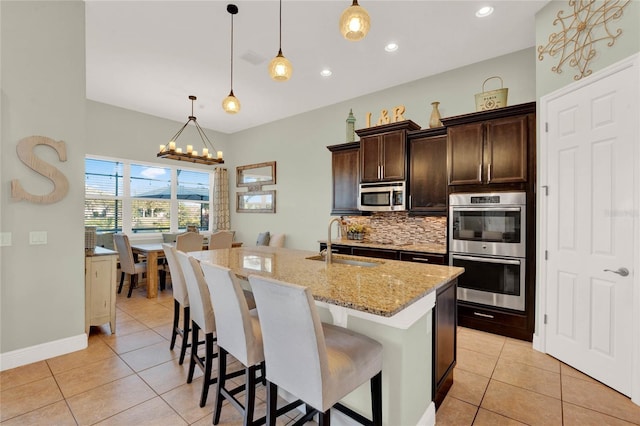 kitchen featuring light tile patterned floors, decorative backsplash, a notable chandelier, stainless steel appliances, and a sink