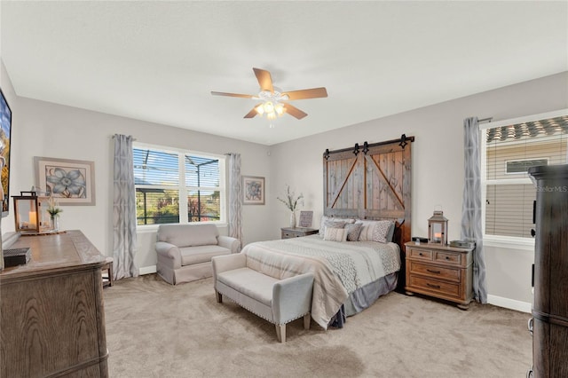 bedroom with light carpet, ceiling fan, baseboards, and a barn door