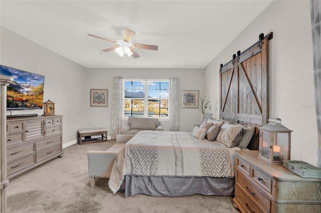 bedroom featuring baseboards, light carpet, a ceiling fan, and a barn door