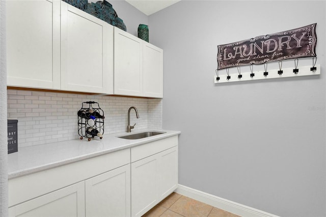 interior space featuring light tile patterned floors, baseboards, and a sink