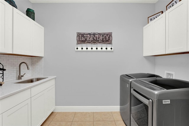 clothes washing area with washer and dryer, a sink, cabinet space, light tile patterned flooring, and baseboards