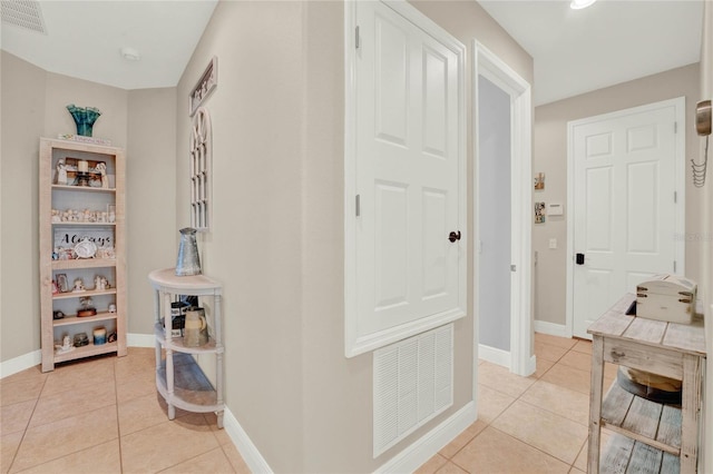 hallway with light tile patterned floors, baseboards, and visible vents