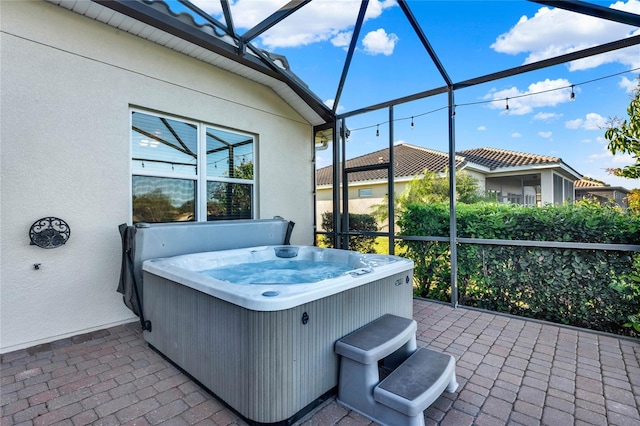 view of patio with glass enclosure, central AC unit, and a hot tub