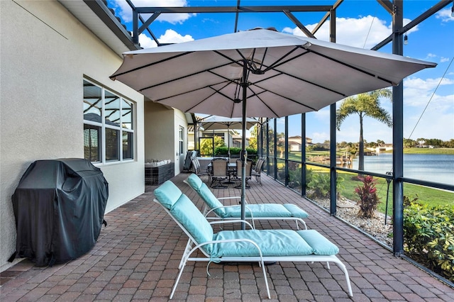 view of patio with glass enclosure, outdoor dining area, a water view, and grilling area