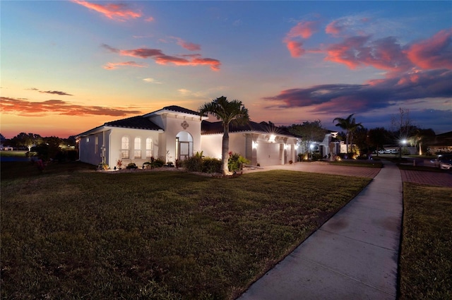 mediterranean / spanish-style home with stucco siding and a yard