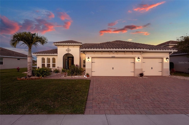 mediterranean / spanish-style home featuring decorative driveway, an attached garage, a front lawn, and stucco siding