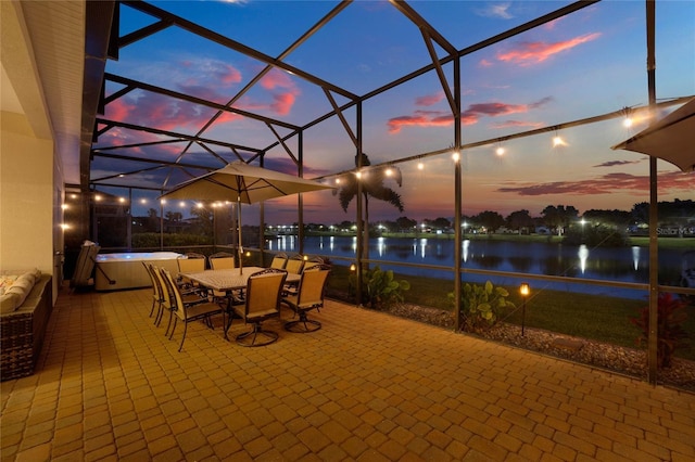 view of patio with outdoor dining space, a lanai, and a water view