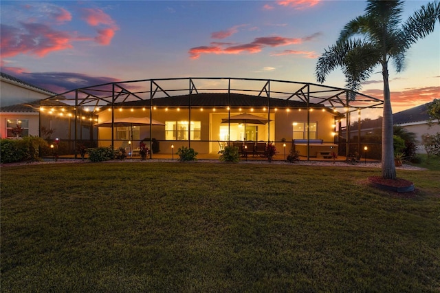 back of house with a lanai, a lawn, and a patio