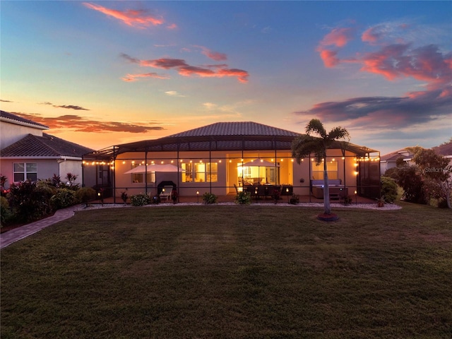 back of property at dusk featuring a patio area and a lawn