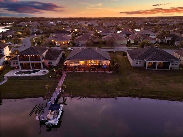 aerial view at dusk with a residential view and a water view