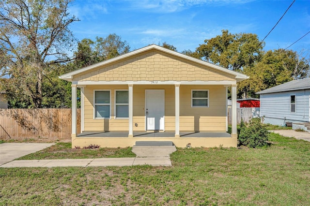 bungalow-style house with covered porch, a front yard, and fence