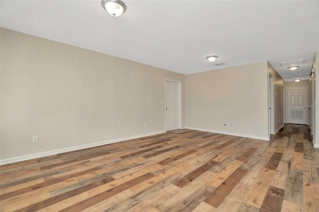 empty room with visible vents, wood-type flooring, and baseboards