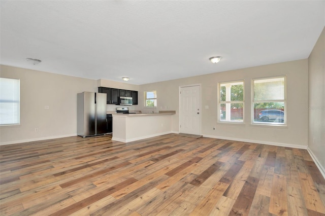 unfurnished living room with baseboards and wood-type flooring