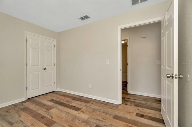 unfurnished bedroom with visible vents, baseboards, and hardwood / wood-style flooring