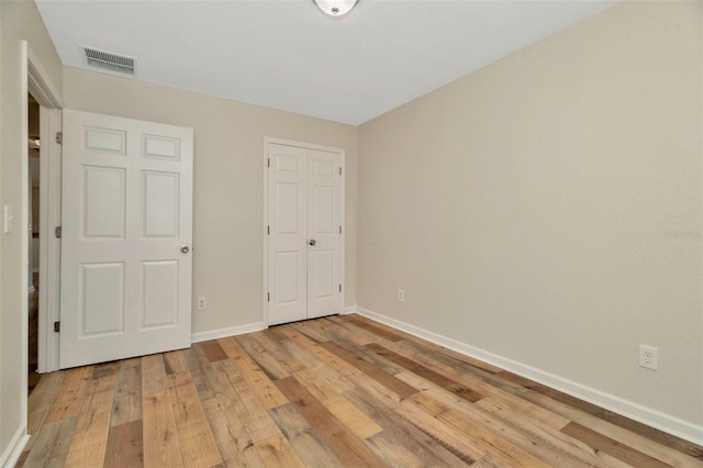 unfurnished bedroom featuring a closet, visible vents, light wood-type flooring, and baseboards