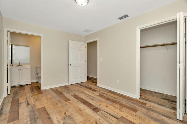 unfurnished bedroom featuring a closet, visible vents, light wood-style flooring, and baseboards