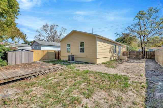 back of house featuring a storage unit, cooling unit, an outdoor structure, and a fenced backyard