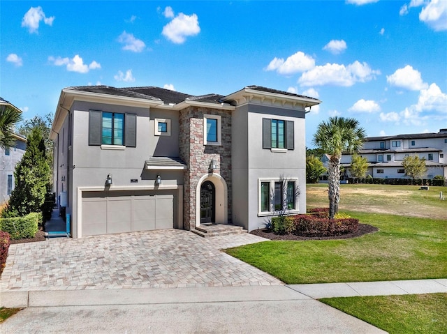 view of front of home featuring decorative driveway, stone siding, a front yard, and stucco siding