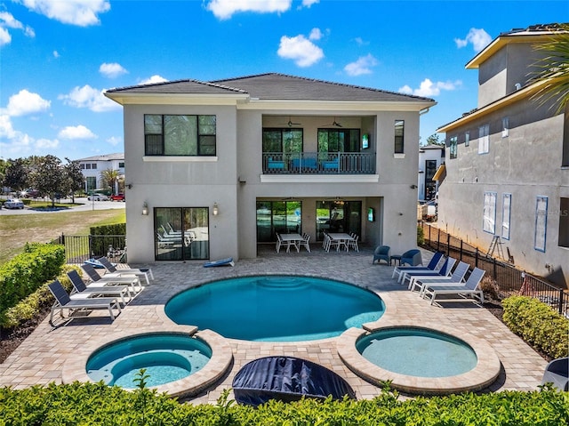 back of property with a patio, a balcony, fence, a pool with connected hot tub, and stucco siding