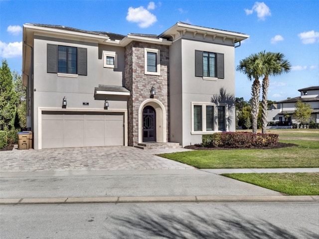 view of front facade featuring stucco siding, a front lawn, a garage, stone siding, and decorative driveway