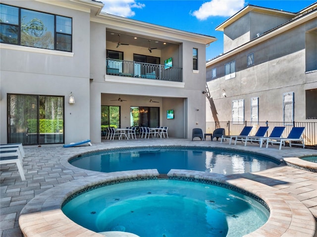 view of pool with a patio, fence, ceiling fan, and a pool with connected hot tub