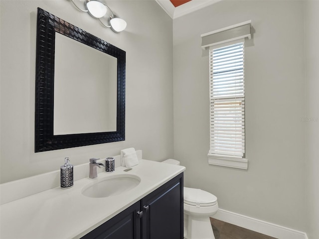 half bath with baseboards, toilet, ornamental molding, and vanity