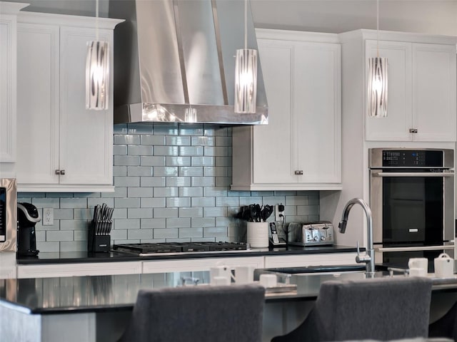 kitchen featuring gas cooktop, backsplash, dark countertops, white cabinetry, and ventilation hood