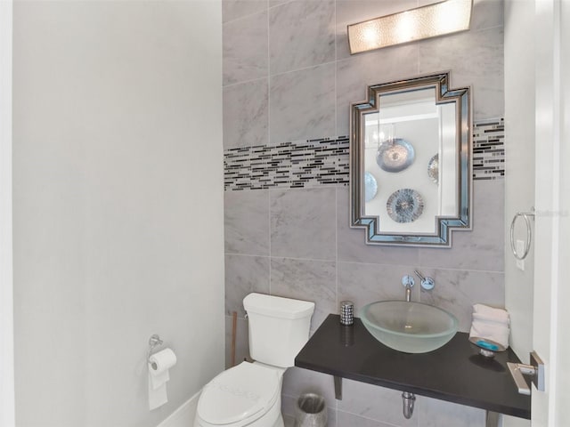 bathroom with tile walls, toilet, and a sink