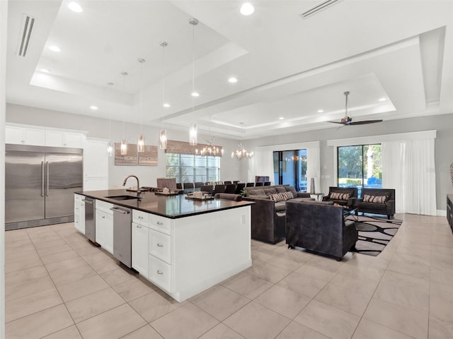 kitchen featuring a sink, a tray ceiling, dark countertops, and stainless steel appliances