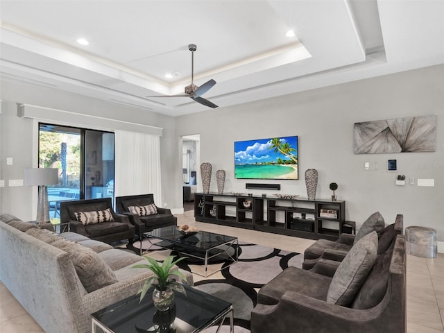 living room with a tray ceiling, light tile patterned floors, recessed lighting, and ceiling fan