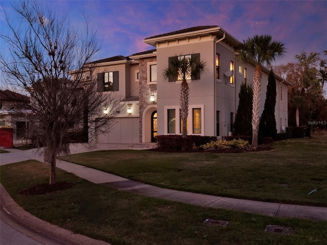 mediterranean / spanish-style home with concrete driveway, an attached garage, a front yard, and stucco siding