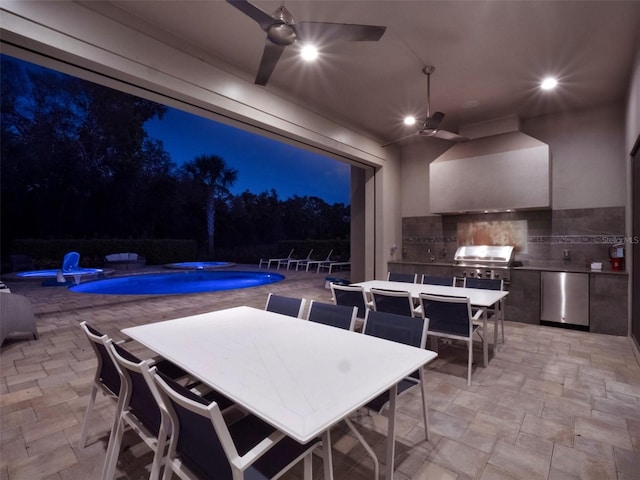 patio at twilight with a fenced in pool, area for grilling, outdoor dining space, and exterior kitchen