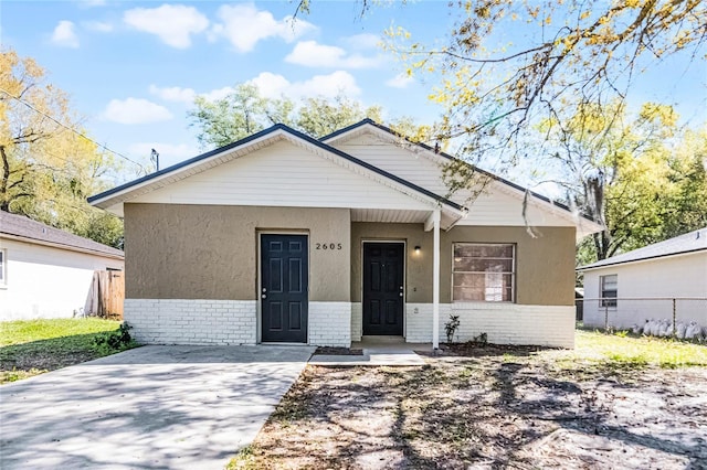 bungalow-style home with fence and brick siding