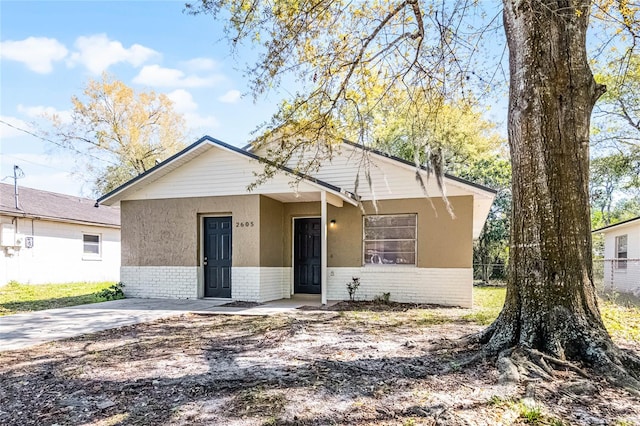 bungalow featuring brick siding and stucco siding